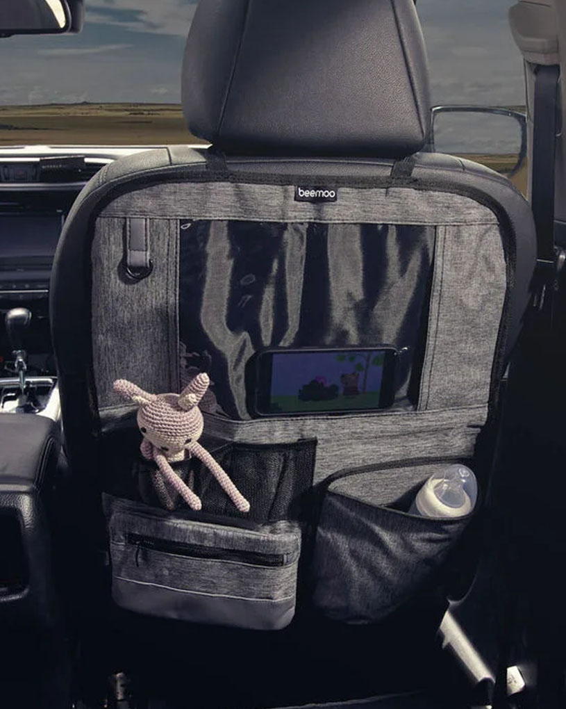 Baksätesskydd med fickor, leksak och nappflaska i en bil.