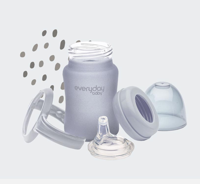 Grå nappflaska med delar och mönstrad bakgrund.