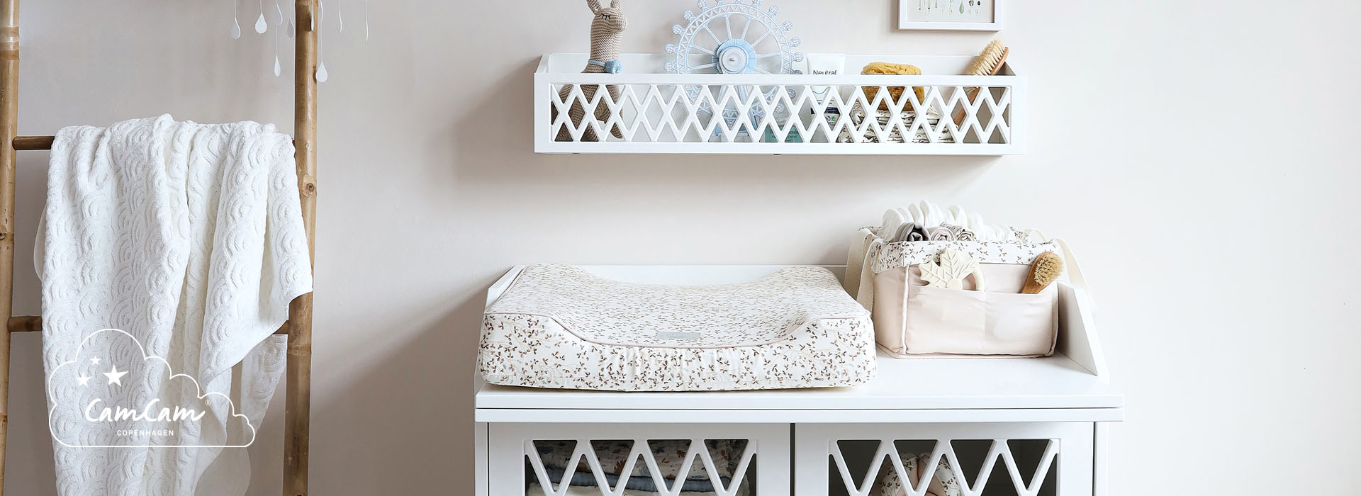 Vitt skötbord med hylla och förvaringskorg, inrett med neutral dekor.