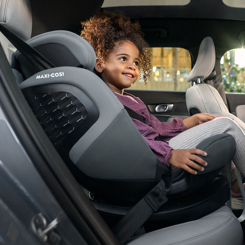 Litet barn i bilstol ler i en bil.