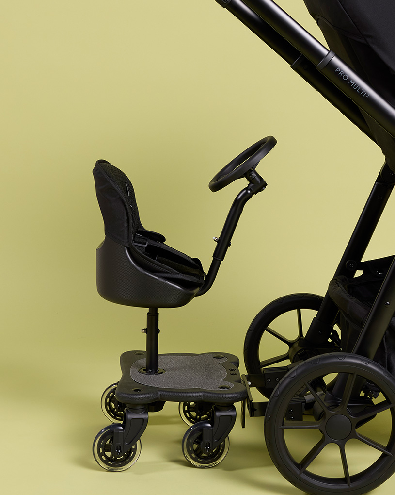 Ett svart ståbräda med sits för barn, anpassad till en barnvagn.