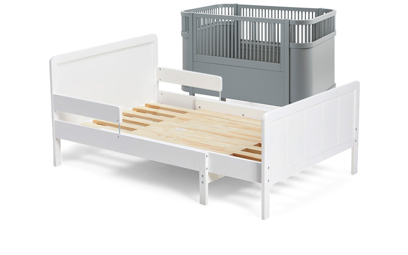 Vitt träbarnsäng med grå barnsäng i bakgrunden.