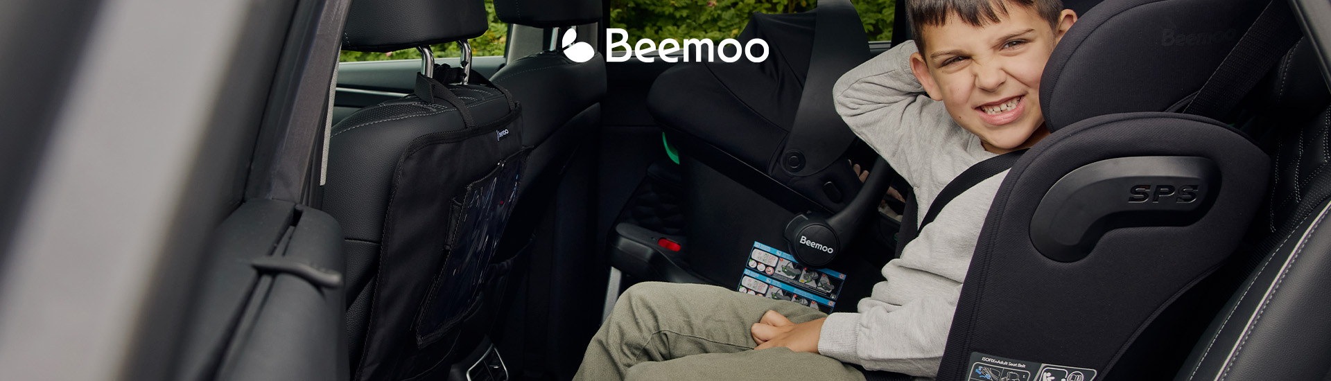 Barn i bilbarnstol bredvid babyskydd i bilens baksäte.