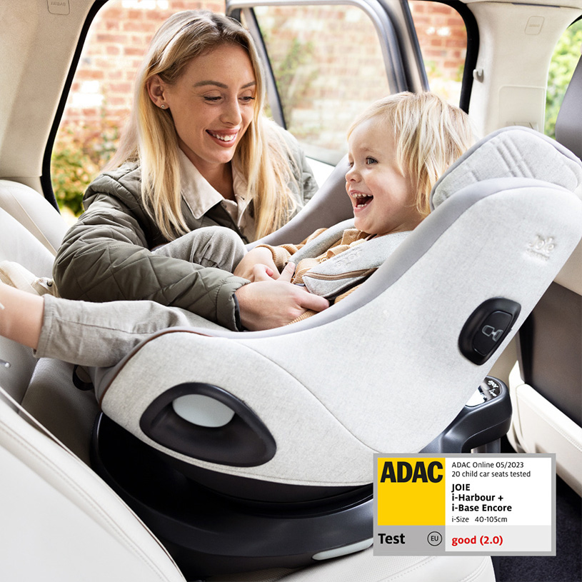 Kvinna ler åt barn i bilbarnstol i bil.