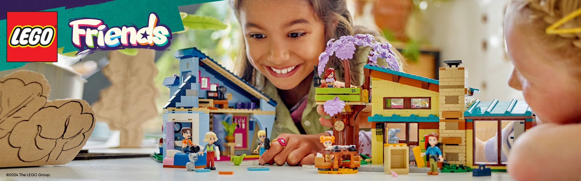 Barn leker med LEGO Friends dockhus och figurer på ett bord.