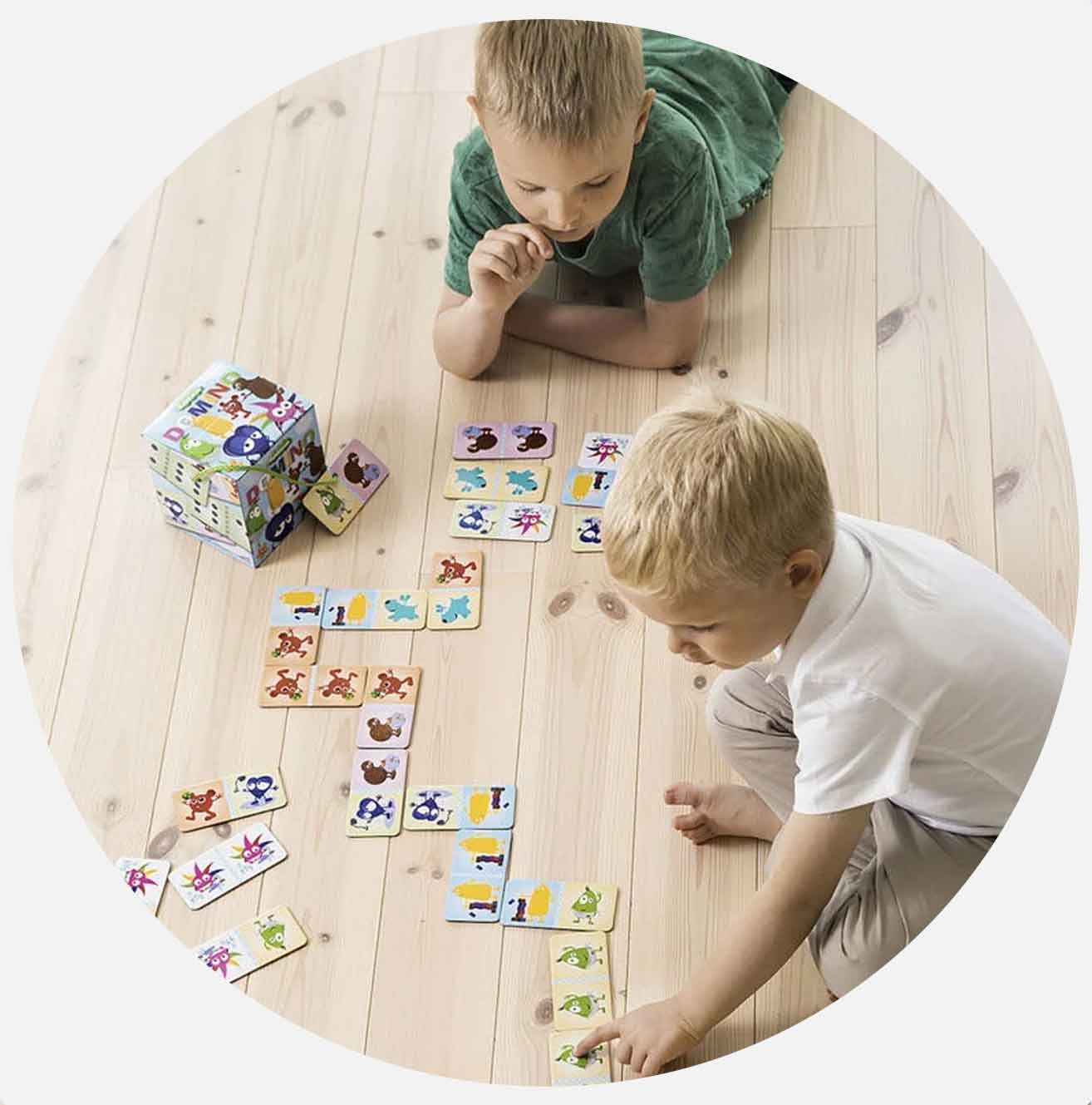 Två barn spelar med djurmotiv på kort på golvet.