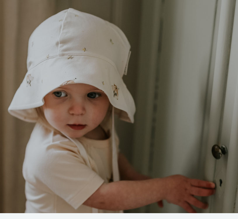 Litet barn i vit hatt tittar mot ett handtag.