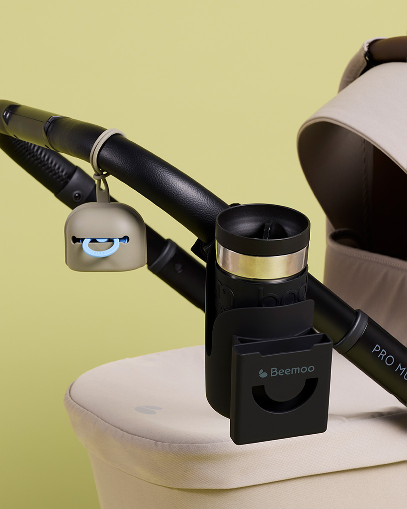 Svart kopphållare till barnvagn med texten 'Beemoo'.