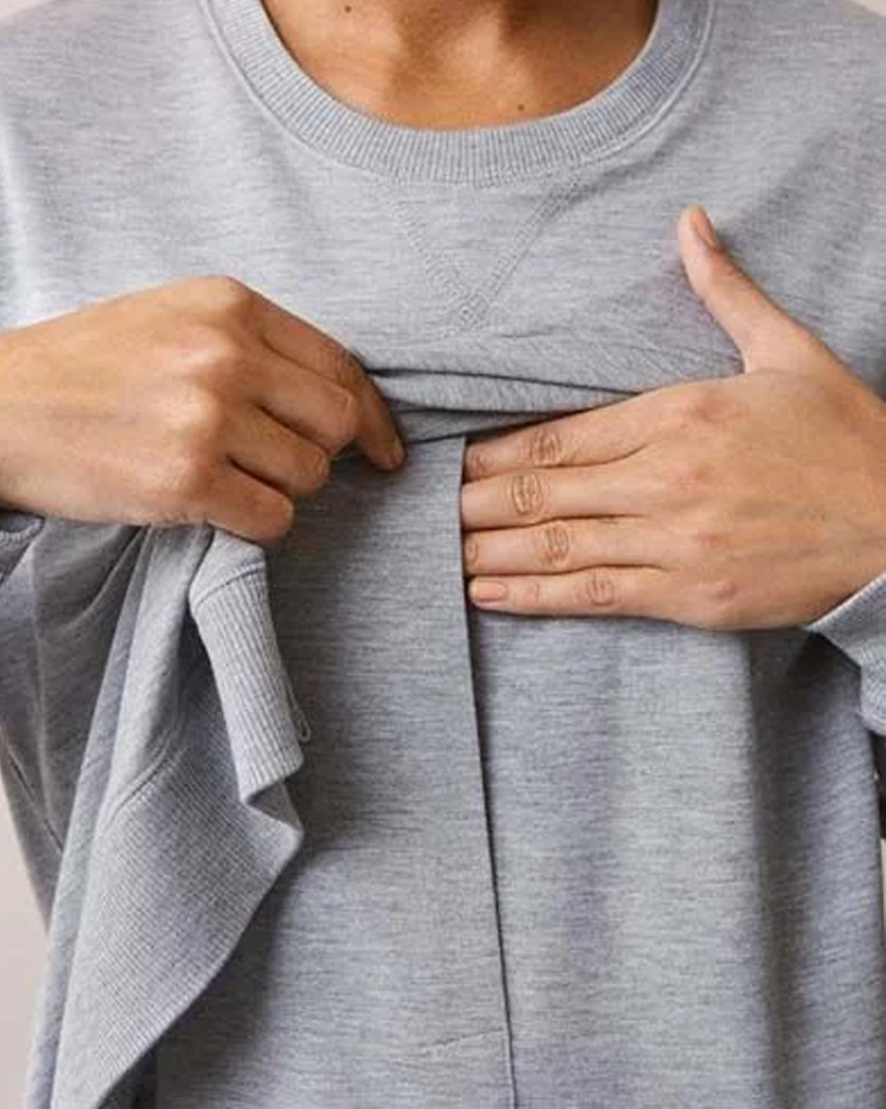 Person visar ficka på grå tröja.