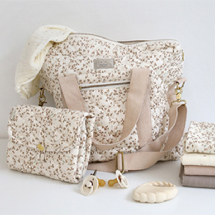 Beige blommig skötväska med matchande accessoarer.