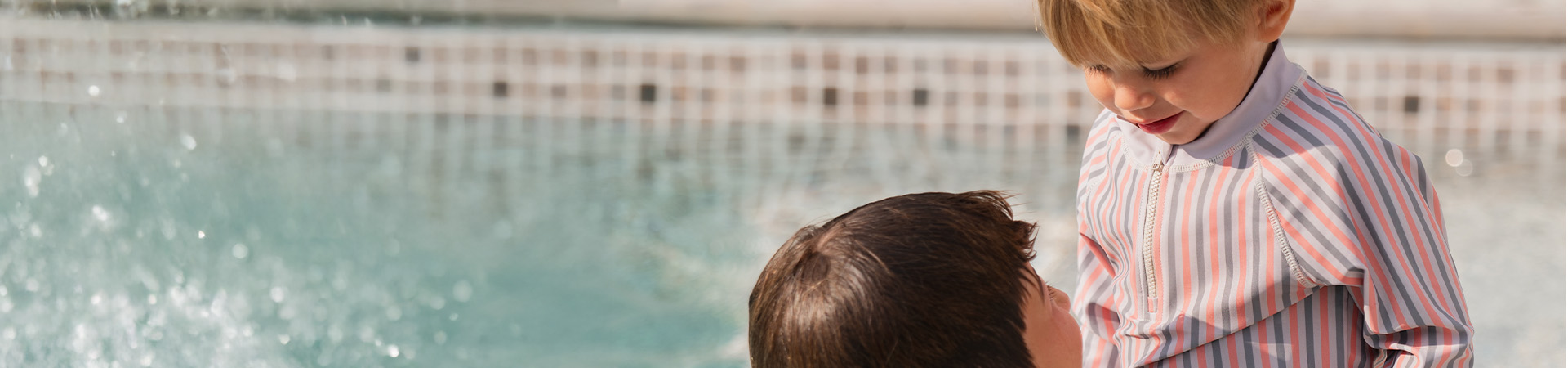 En mamma ler mot sitt barn som håller en blomma, med texten 'Kenza X Viking'.