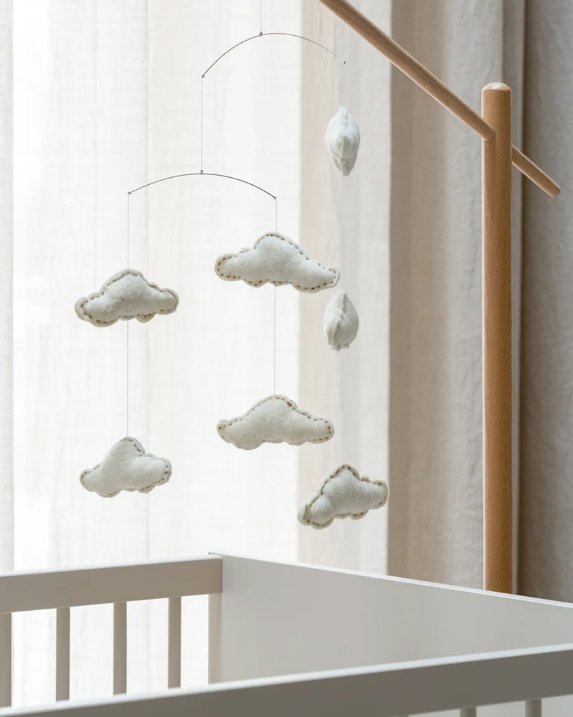 Spjälsängsmobil med mjukisdjur och gröna hjärtan.