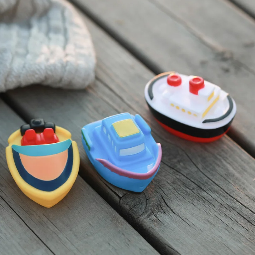 Tre färgglada leksaksbåtar på en träyta.