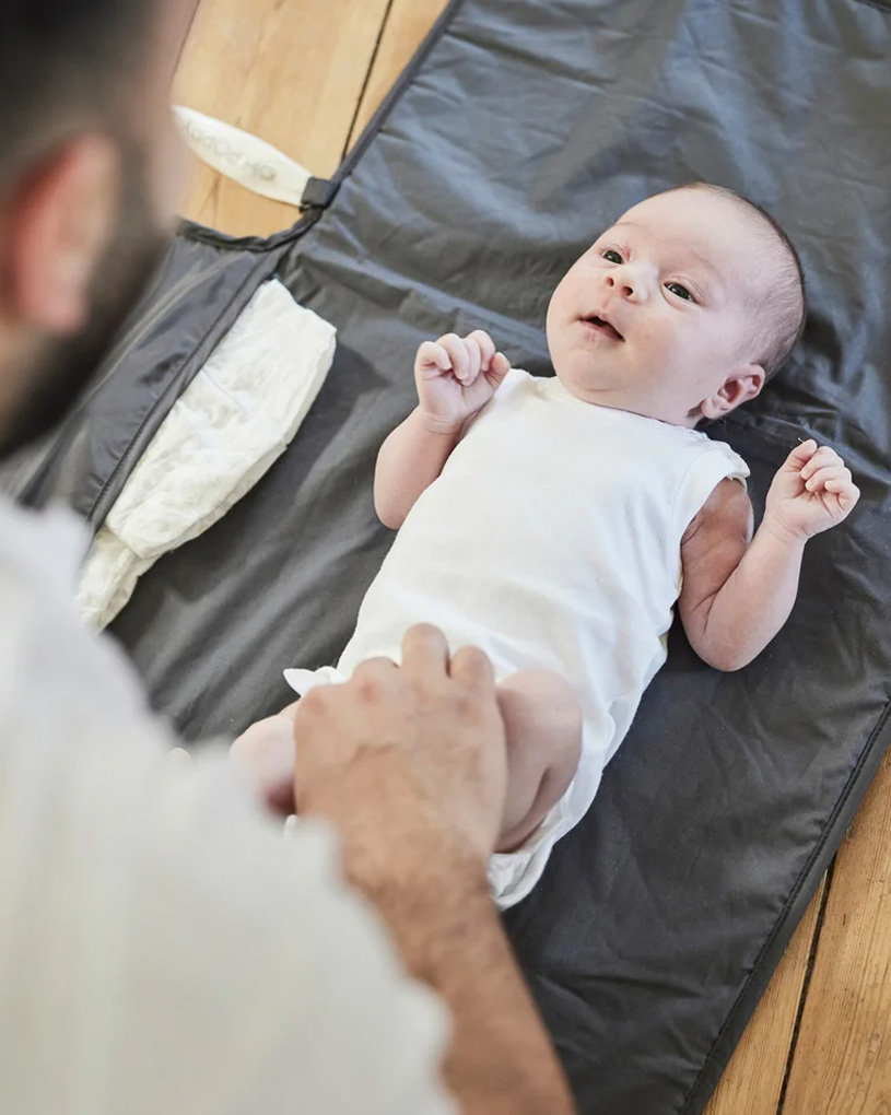 Grå barnvagn med en liten grå förvaringsväska på handtaget.