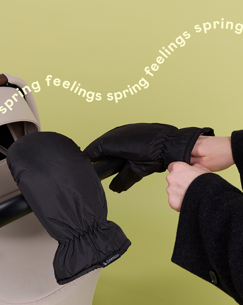 Två svarta barnvagnsvantar på en barnvagn med texten 'spring feelings spring feelings'.