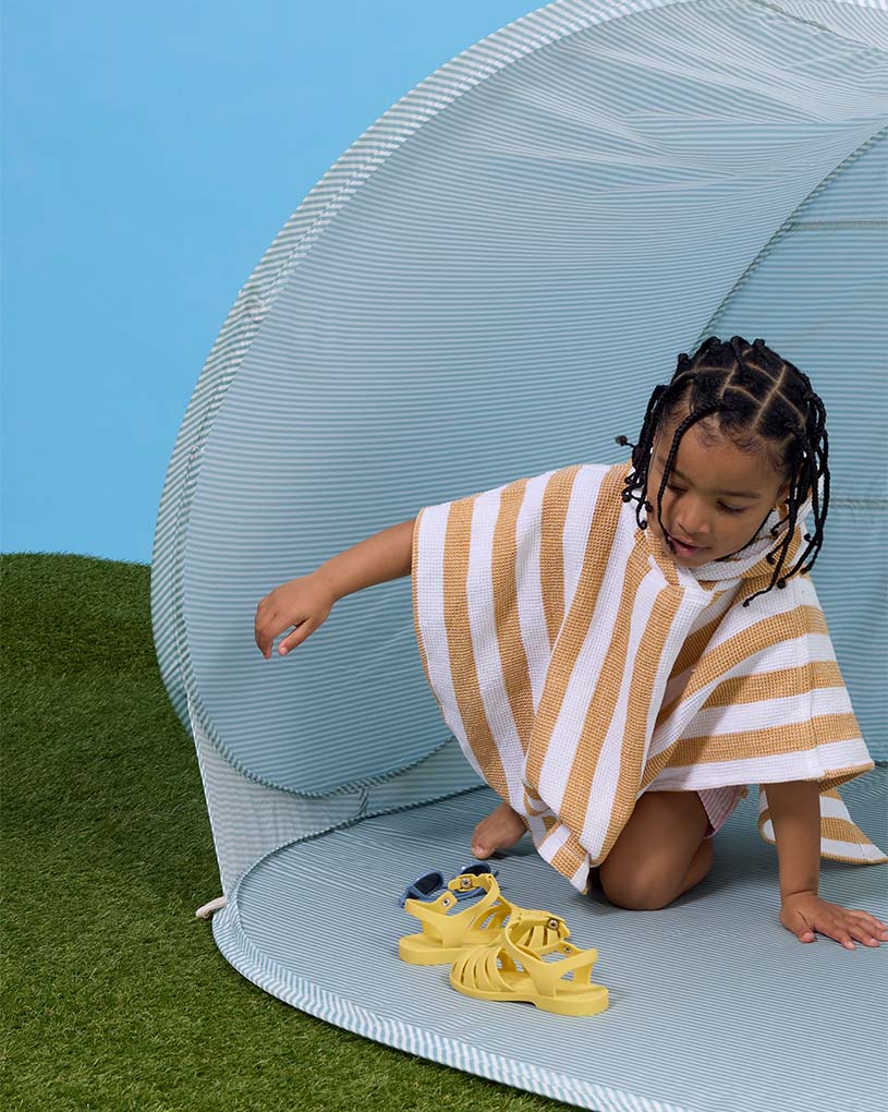 Två barn leker i ett strandtält på sandig strand, text: 'Nyhet!'.