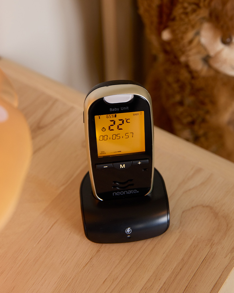 Sovande bebis i spjälsäng med babyvakt på nattduksbord.