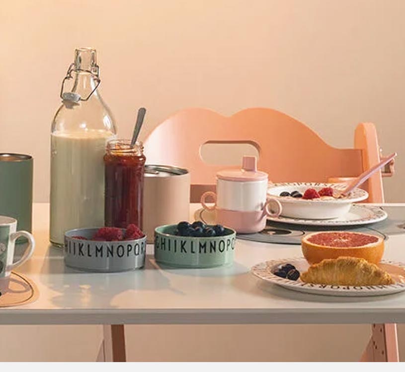 Frukostbord med juice, sylt och frukt i färgglada skålar.