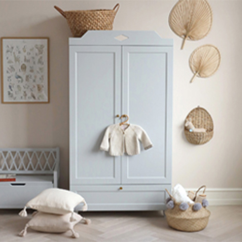 Grå garderob med babytröja, korgar och dekor i barnrum.