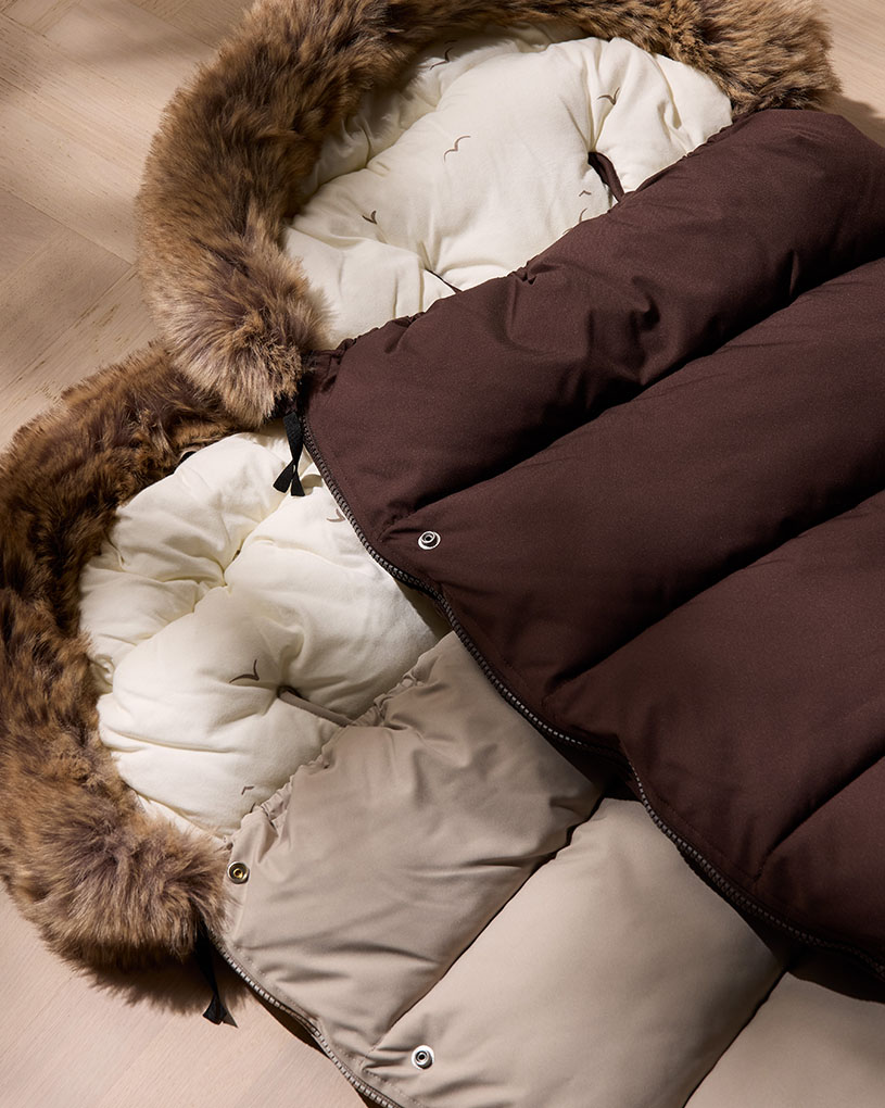 Bebis i nalleinspirerad overall i barnvagn, leende.