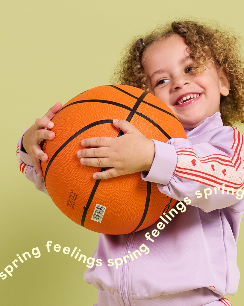 Barn kramar en orange basketboll med texten 'spring feelings spring feelings spring'.
