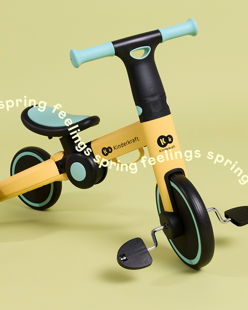 En gul trehjuling med svart styre och texten 'spring feelings'.