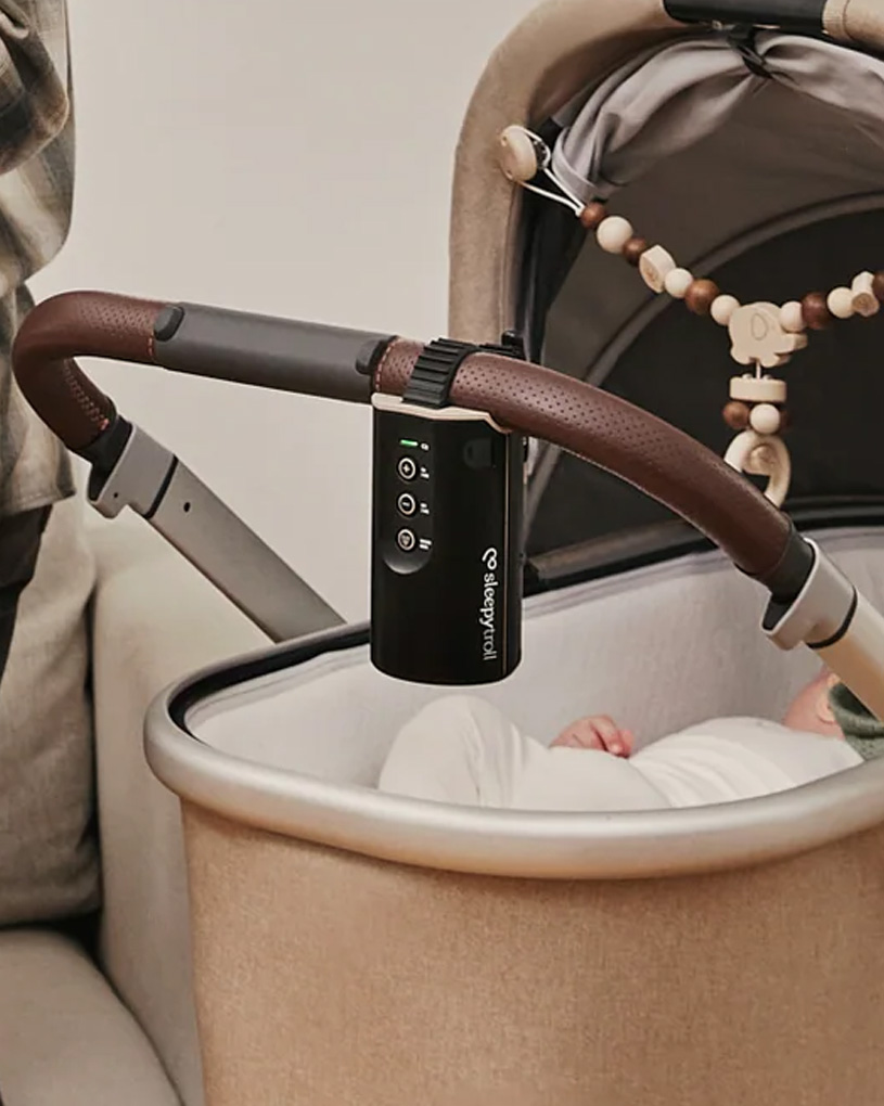 Svart babysovhjälp fäst vid vagn, sovande bebis under.