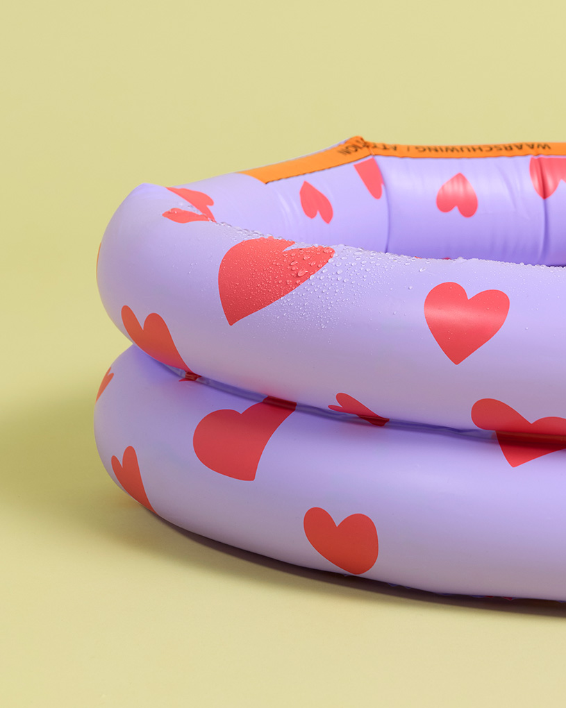 Två uppblåsbara pooler i lila med röda hjärtan, med texten 'Vattenaktivering'.