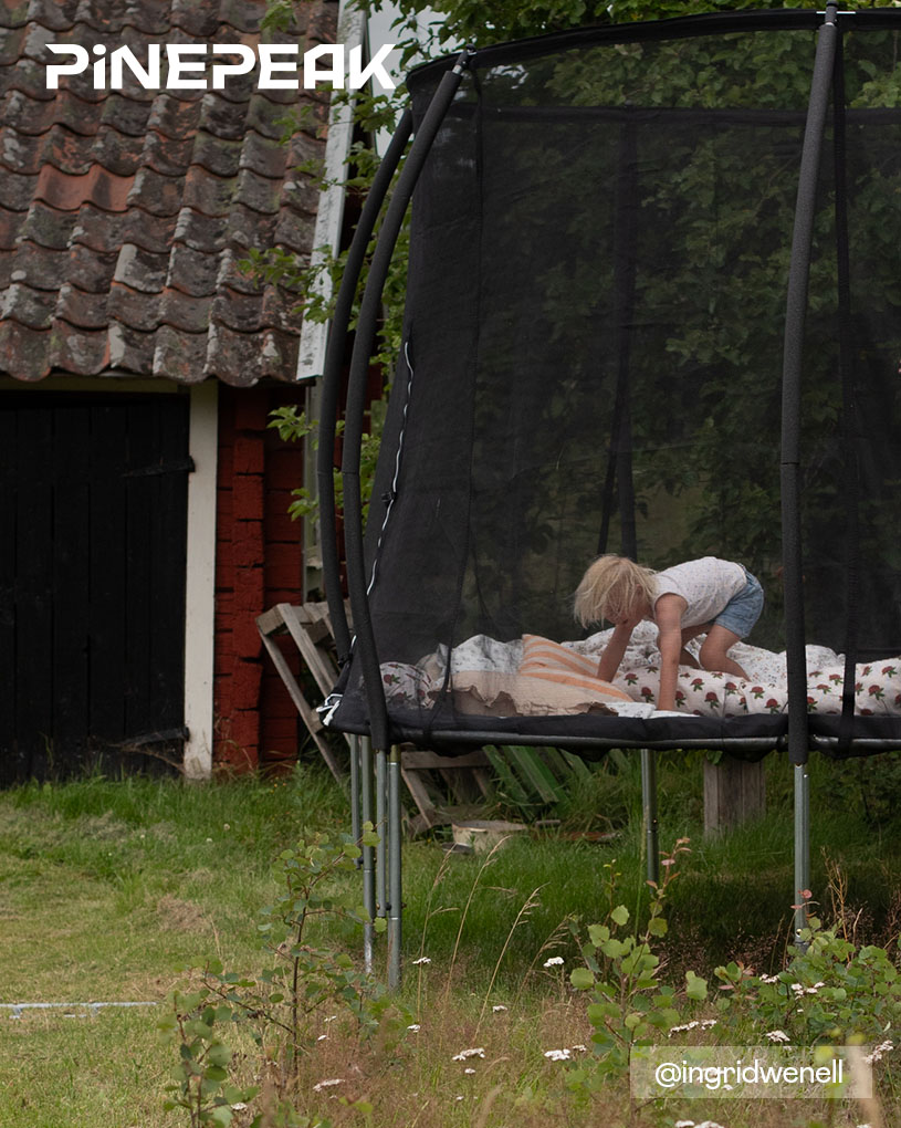 Barn leker på en trampolin med texten 'PINEPEAK'.