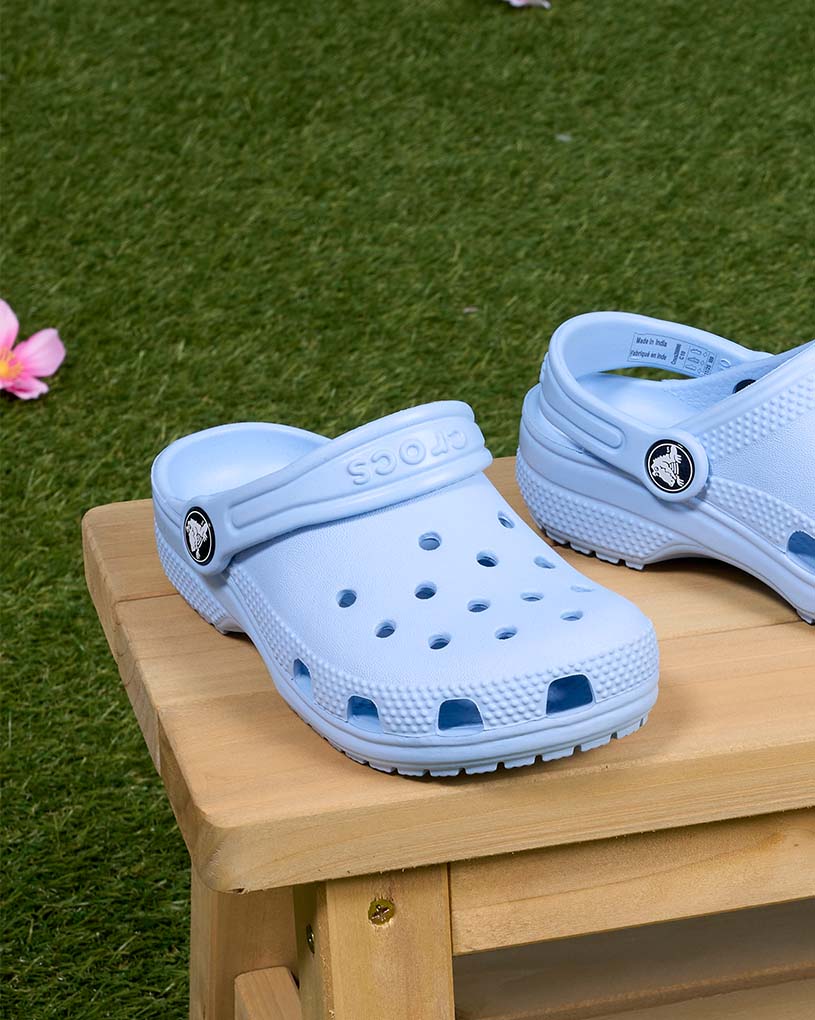 Barn in sandaler går på träterrass.