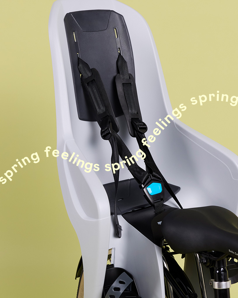 Cykelsäte med säkerhetsremmar och texten 'spring feelings spring'.