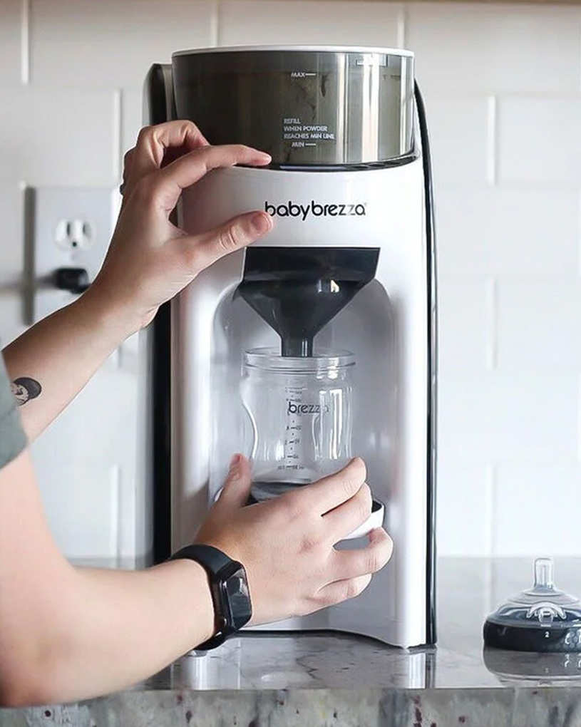 Person använder en Baby Brezza-maskin för att förbereda nappflaska.