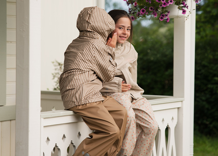 Två barn sitter på en balkong och viskar till varandra, med texten 'Kenza X Viking'.