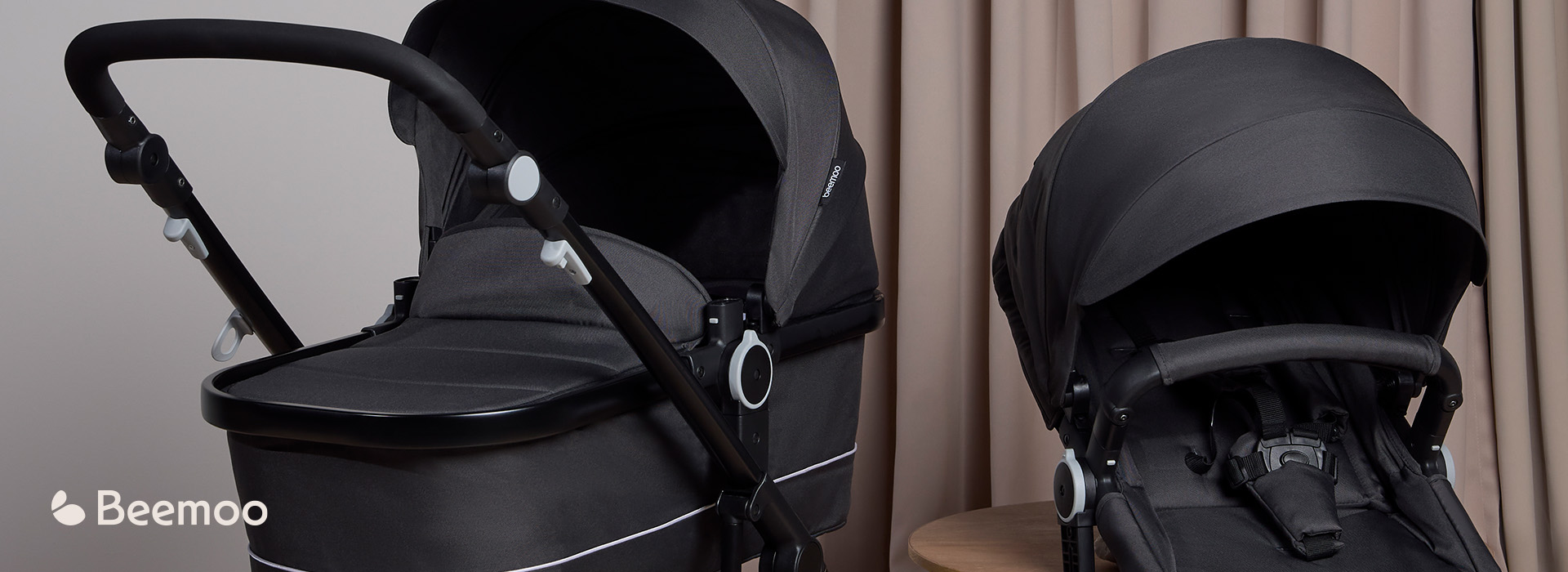 Svart barnvagn i ett ljust rum, texten 'MOVE' och 'Beemoo'.