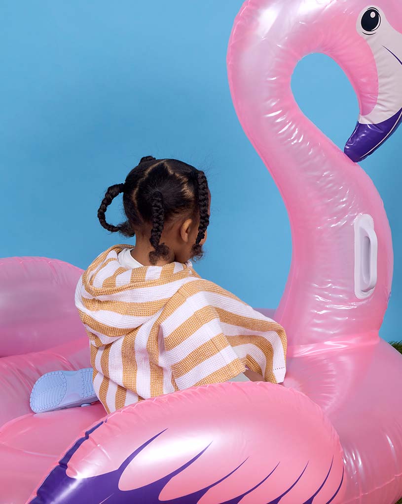 Barn i randig overall bär simring med krabbor på strand.