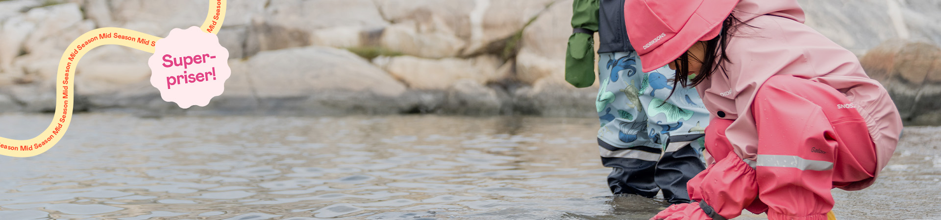 Barn i rosa regnkläder leker i vatten, etikett “Super-priser!” i hörnet
