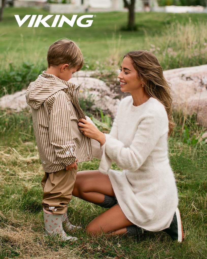 Flicka med flätor och mönstrad jacka, sitter på uteplats.