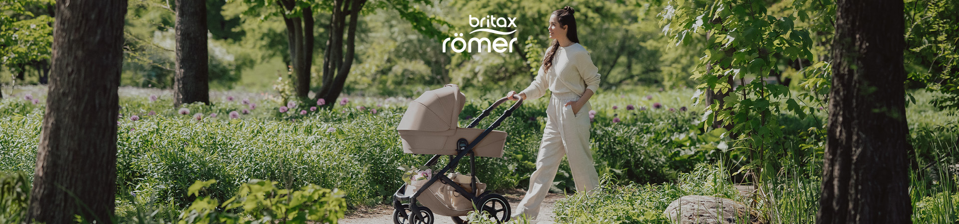 Kvinna går med barnvagn i en grön park, med texten 'britax'.