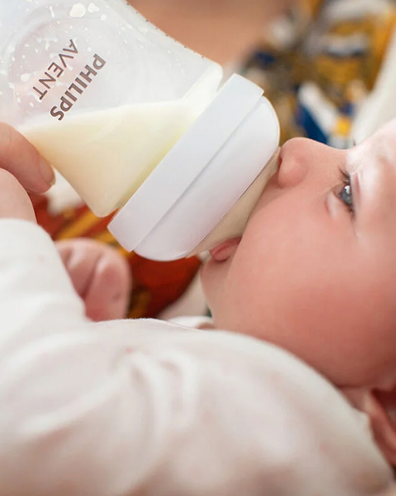 Bebis dricker mjölk från nappflaska.