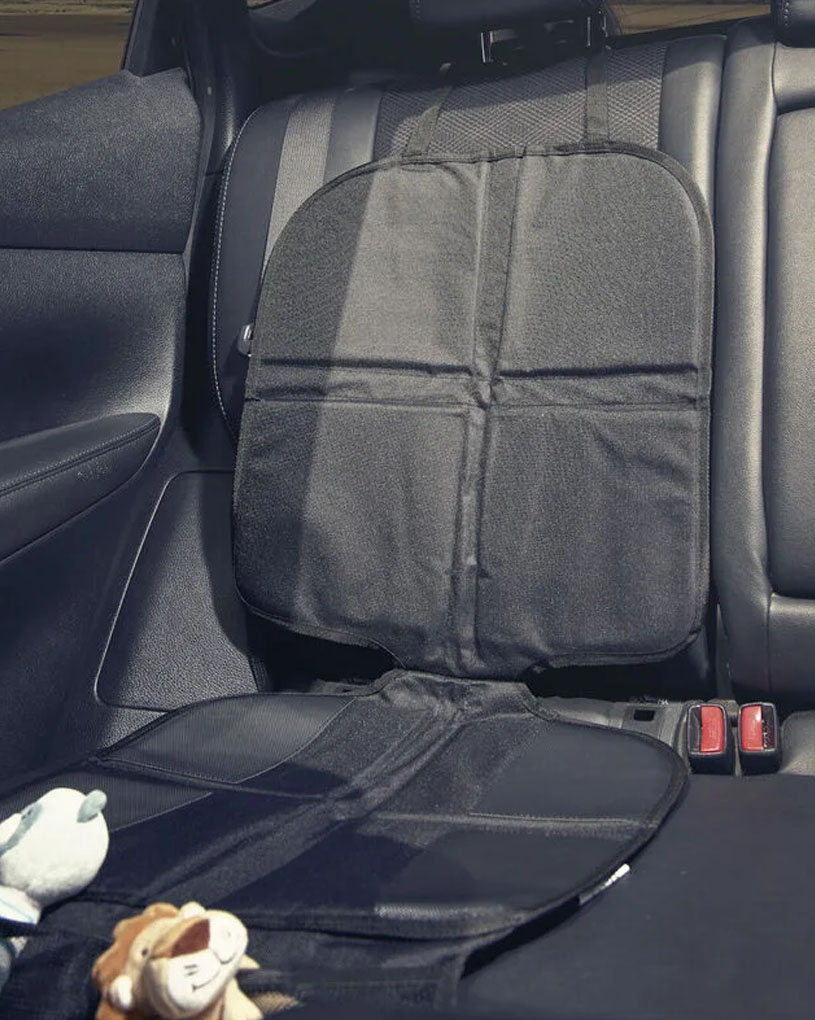 Bilbarnstolsskydd på baksätet med leksaker framför.