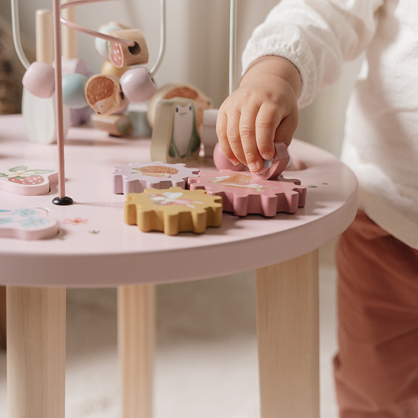 Barnlek med träklossar på ett rosa bord.