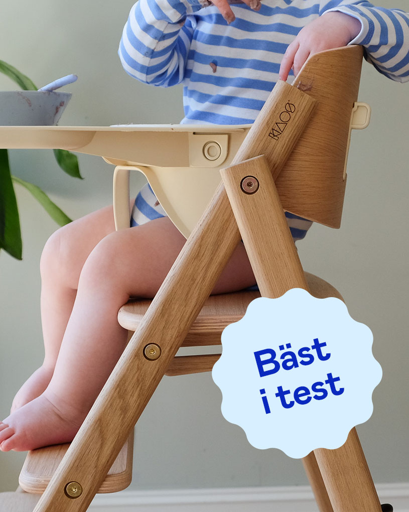 Bebis i beige BabyBjörn-bärsele med blå etikett 'Bäst i test'.