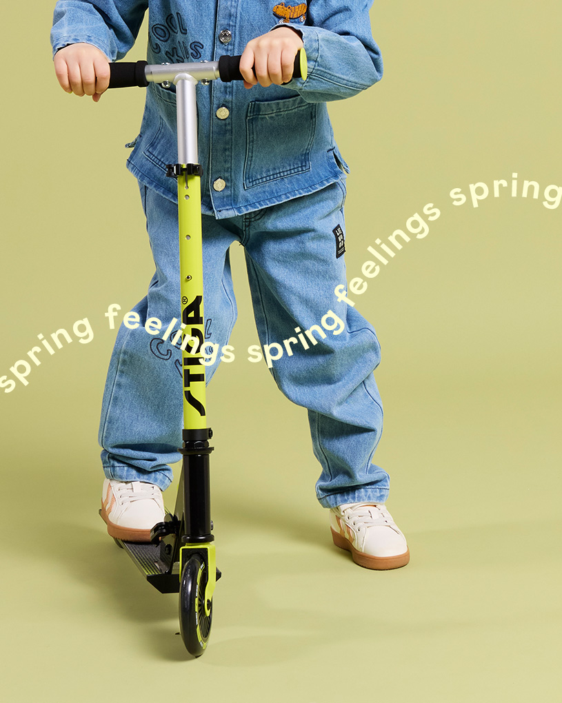 Barn står på en sparkcykel med texten 'spring feelings spring feelings spring'.